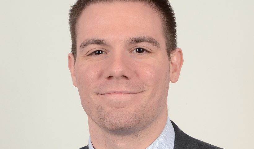 Professional headshot of smiling man in suit
